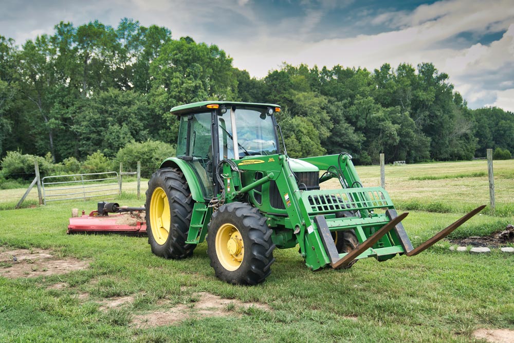 A John Deere tractor, agricultural machinery hire, tractor against a green field