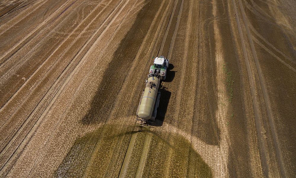 Aerial view of a tractor spreading fertiliser on a field, digestate spreading
